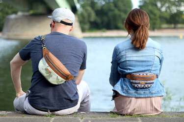 Zwei Personen von hinten mit gemusterten Bauchtaschen: eine hellgrün mit geometrischem Muster, die andere dunkelblau mit Tribal-Muster.