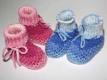 Zweifarbige, handgestrickte Babyschuhe in Pink und Blau mit geripptem Bündchen und Bindeband.