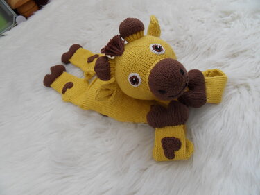 Gestricktes gelb-braunes Giraffen‑Schmusetuch auf hellem Fell