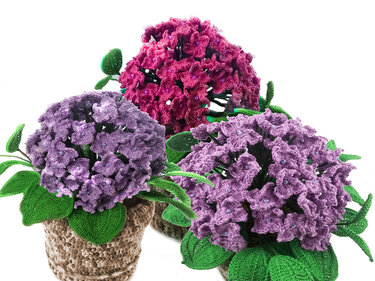 Drei gehäkelte Hortensien in Lila und Pink in gehäkelten Töpfen