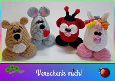 Vier gehäkelte Amigurumi-Figuren auf weißem Hintergrund: brauner Bär, graue Maus mit rotem Herz, roter Marienkäfer und weißes Einhorn mit bunter Mähne.