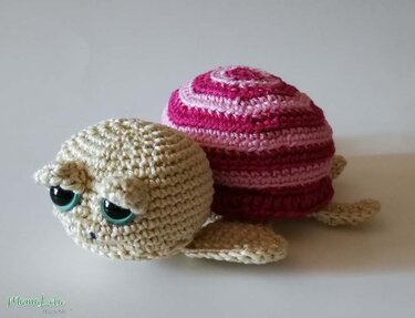 Amigurumi-Schildkröte gehäkelt mit beigem Kopf und rosa/dunkelrosa gestreiftem Panzer
