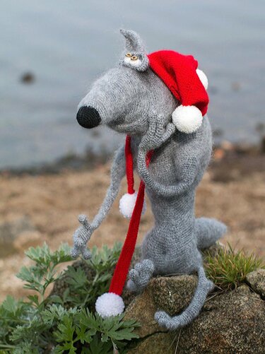 Grey crochet amigurumi with button on ear, long snout, and red pom-pom hat
