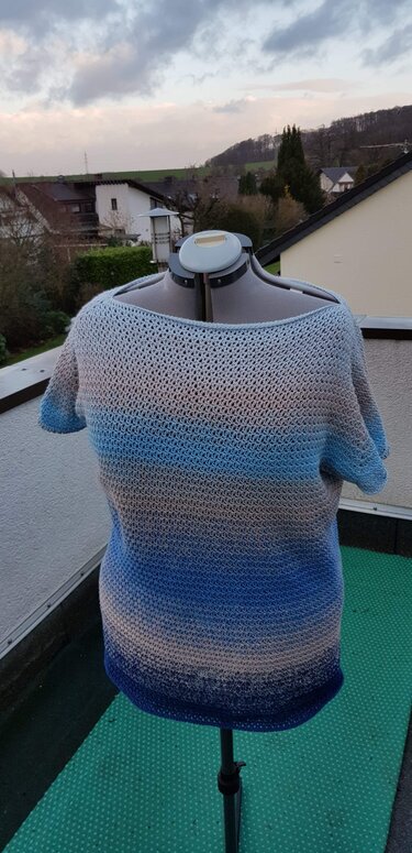 Rückansicht gehäkeltes Kurzarmshirt in blau-beige Farbverlauf auf Schneiderpuppe auf Balkon