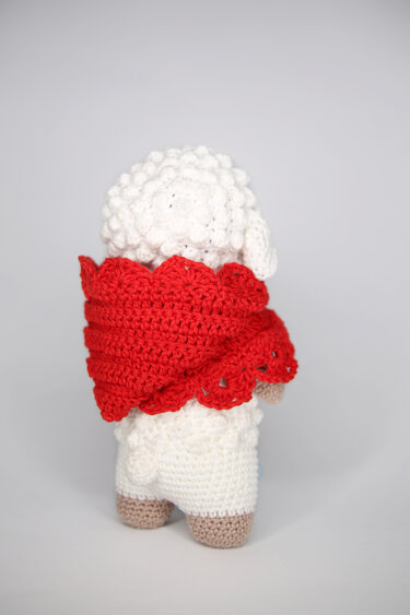 Rückansicht eines gehäkelten Lamm-Amigurumi mit rotem Umhang