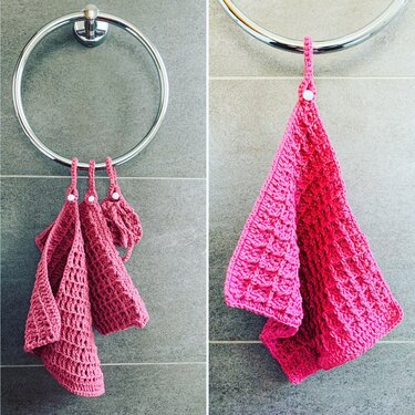 Gehäkelte rosa Handtücher mit Schlaufen und weißen Druckknöpfen an einem Metallring vor grauen Fliesen