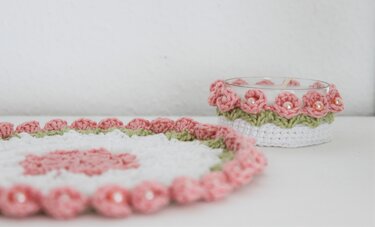 Weißes gehäkeltes Deckchen und passender Kerzenhalter mit rosa Blüten und Perlen