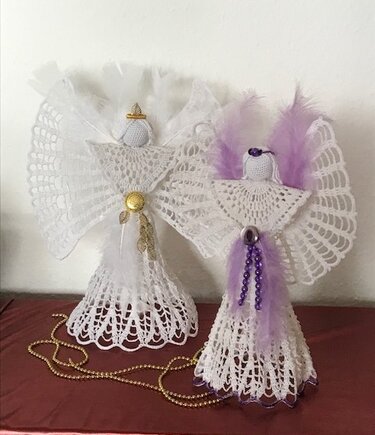Zwei gehäkelte Weihnachtsengel mit Spitzenröcken, gefächerten Flügeln, Perlenakzenten und Federn, einer in Weiß, einer mit violetten Details