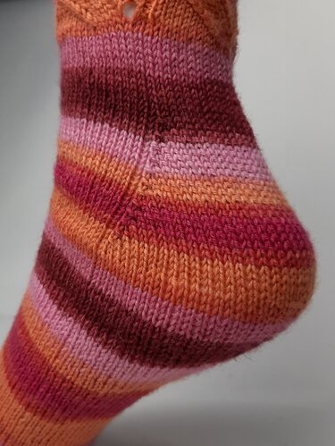 Detailansicht einer gestrickten Socke mit Ferse und Lochmuster
