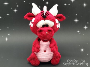 Roter gehäkelter Amigurumi-Drache mit weißen Hörnern und rosa Bauch