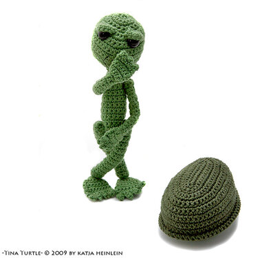 Green crocheted turtle amigurumi standing with removable shell on white background