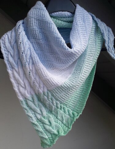 Gestricktes Dreieckstuch in Hellblau, Weiß und Mintgrün mit Zopf- und Lochmuster, an Kleiderbügel hängend.