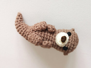 Braunes gehäkeltes Otter-Amigurumi mit weißer Schnauze und schwarzen Augen