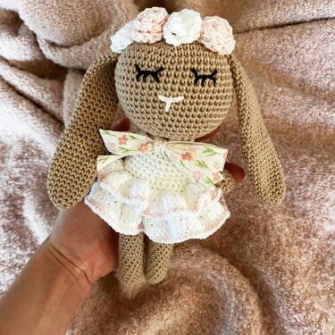 Brauner Amigurumi-Schlappohrhase mit weißem Rüschenkleid, Blumenschleife und gehäkeltem Blumenkranz