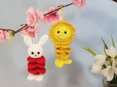 Gehäkelte Amigurumi-Anhänger: Hase mit rotem Rüschenkörper und gelbe Sonne mit Gesicht