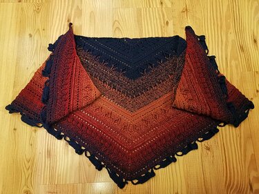 Gehäkeltes Dreieckstuch mit Farbverlauf von Dunkelblau zu Rostrot auf Holzboden