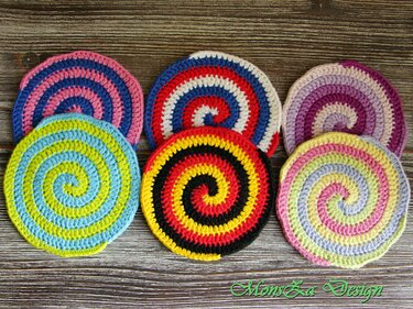 Sechs gehäkelte runde Untersetzer mit Spiralstreifen auf Holzuntergrund