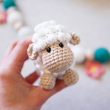 Close-up of amigurumi sheep showing crochet stitches, beige muzzle and tiny legs