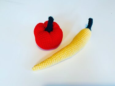 Gehäkelter roter Paprika und gelbe Chilischote auf weißem Hintergrund