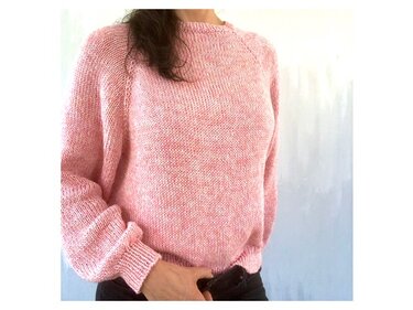 Woman wearing a pink raglan crewneck knit sweater with ribbed cuffs