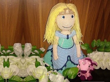 Gehäkelte Prinzessin mit blondem Haar, blau-mintfarbenem Kleid und Krone, daneben ein kleines rosa Häkeltier