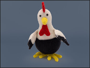 Gehäkeltes Amigurumi‑Huhn in Weiß, Schwarz, Gelb und Rot auf schlichtem Hintergrund.