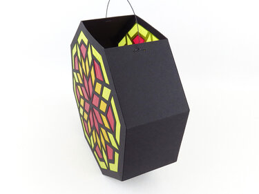 Schwarze sechseckige Papierlaterne mit gelb-rotem Mosaikmuster und Drahtbügel