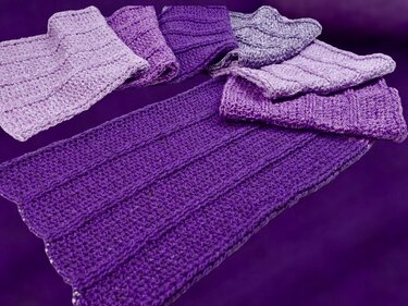 Mehrere gehäkelte Schals in Lila- und Violetttönen mit Rippenmuster