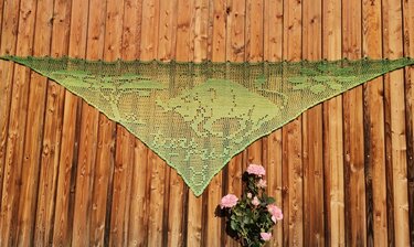 Grünes Filet-Dreieckstuch mit Waldmotiv, Farbverlauf und Maschenstruktur an Holzwand