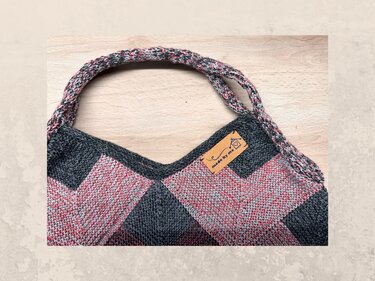 Gestrickte Damen-Schultertasche grau-rosé mit gedrehtem Tragegriff und Lederetikett