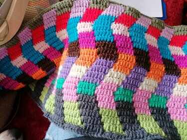 Nahaufnahme einer bunten gehäkelten Decke mit farbigen Quadraten