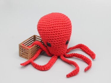 Rotes gehäkeltes Amigurumi-Oktopus mit schwarzen Augen und langen Tentakeln