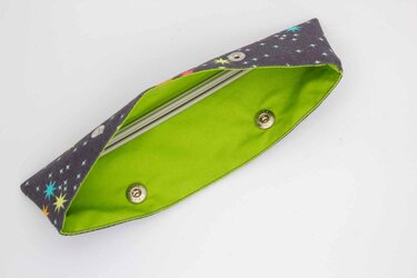 Geöffnetes Stoffetui mit buntem Sternenmuster außen und neongrünem Innenfutter, zwei Druckknöpfe sichtbar