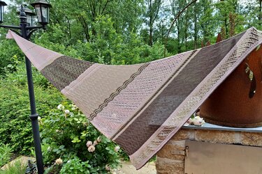 Gestricktes Dreieckstuch in Pastellrosa und Braun, aufgespannt im Garten