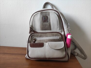 Beiger Rucksack mit pinker gehäkelter Hülle für Lippenbalsam am Karabiner