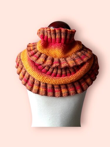 Gestrickter Loop-Schal in Rot, Orange und Gelb mit gestuften Rüschen und geripptem Rollkragen auf einer Schaufensterform