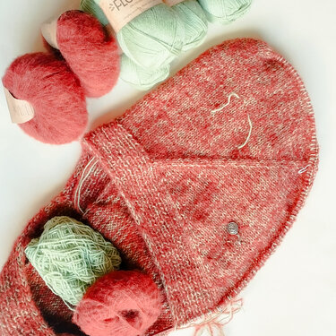 Halbfertiges Strickstück mit roten und mintgrünen Garnen, Maschenmarkierer sichtbar