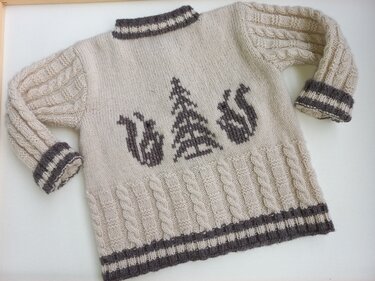 Beigefarbener, handgestrickter Kinderpullover mit Eichhörnchen, Tannenbaum und Zopfmuster