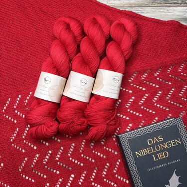 Rotes Dreieckstuch mit Zickzack-Lacemuster und drei roten Garnsträngen