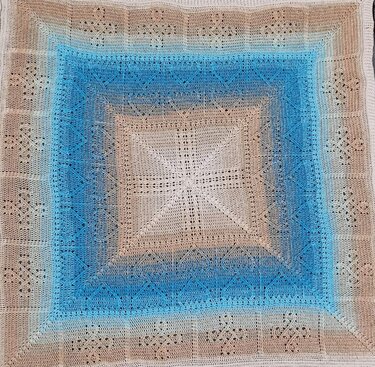 Quadratische gehäkelte Decke mit beige‑blauem Farbverlauf und sternförmigem Zentrum