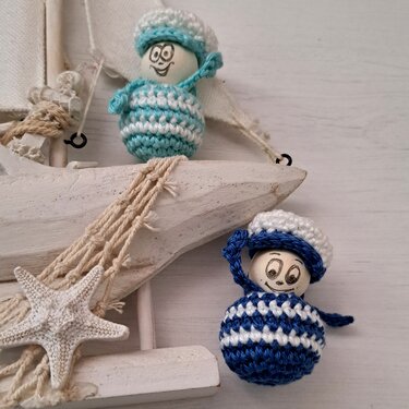 Nahaufnahme zweier schnell gehäkelter Matrosen-Amigurumi mit gestreiften Körpern und kleinen Häubchen