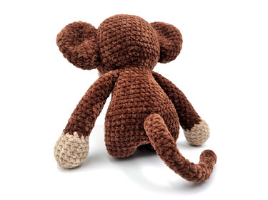 Gehäkelter brauner Amigurumi-Affe von hinten mit langem Schwanz und hellen Pfoten