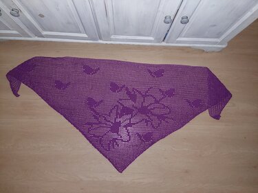 Lila gehäkeltes Dreieckstuch mit Herz- und Blumenmotiv, flach auf dem Boden ausgelegt