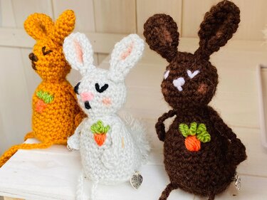 Handgehäkelte Osterhasen aus Garn in Gelb, Weiß und Braun mit gestickten Karottenmotiven