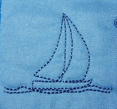 Stilisierte Stickerei eines Segelbootes mit zwei Segeln und Wellen in Dunkelblau auf hellblauem, strukturiertem Stoff