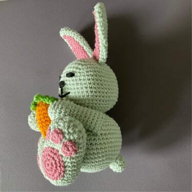 Gehäkelter mintgrüner Hase mit rosa Details und orangefarbener Karotte