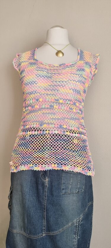 Gehäkeltes pastellfarbenes Netz-Top mit kurzen Ärmeln auf Schaufensterpuppe über Jeansrock