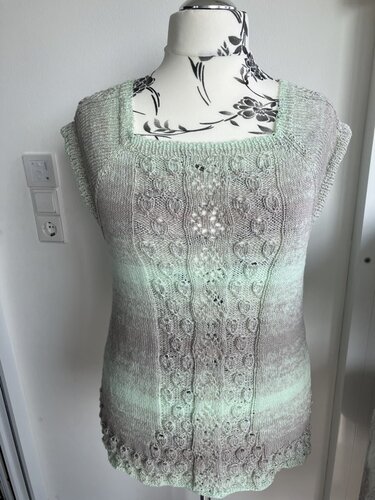 Mint‑beiges Stricktop mit Ajour- und Zopfmuster auf Schneiderpuppe, quadratischer Ausschnitt