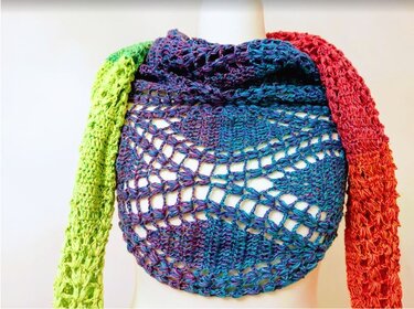 Gehäkeltes Dreieckstuch mit offenem Spitzenmuster in Blau-Violett, grünen und roten Schenkeln auf Büste