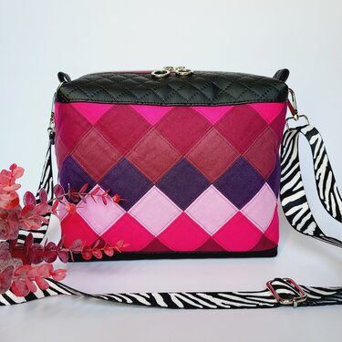 Gesteppte Umhängetasche in Pink und Lila mit Rautenmuster, schwarzer gesteppter Klappe und Zebra-Schultergurt.
